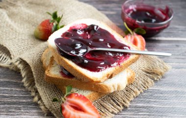 Strawberry jam, bread, fresh berry on a wooden background