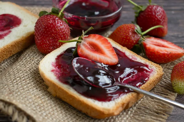 Strawberry jam, bread, fresh berry on a wooden background