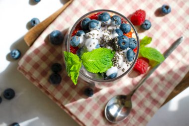 Yogurt, chia seeds, raspberries, strawberries, blueberries, mint on a light background