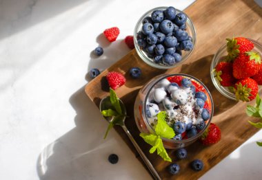 Yogurt, chia seeds, raspberries, strawberries, blueberries, mint on a light background