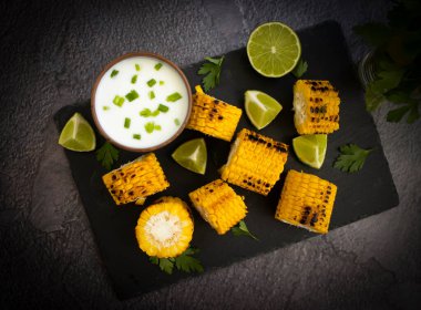 Grilled corn, lime on a dark background