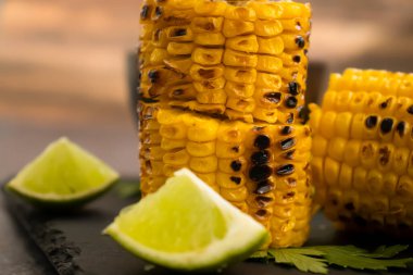 Grilled corn, lime on a dark background