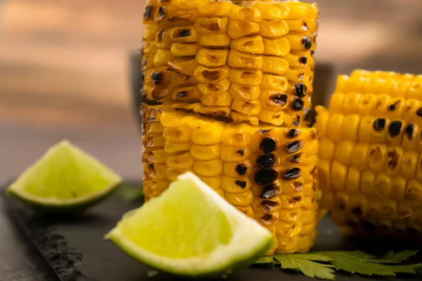 Grilled corn, lime on a dark background