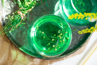 Water with tarragon grass on a light background