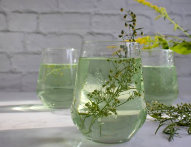 Water with tarragon grass on a light background