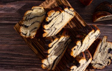 Appetizing bun with poppy seeds on an old background