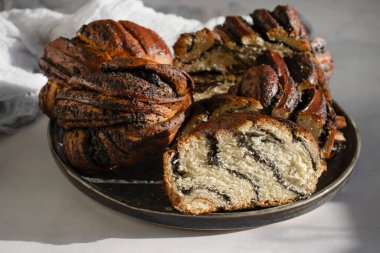 Appetizing bun with poppy seeds on an old background