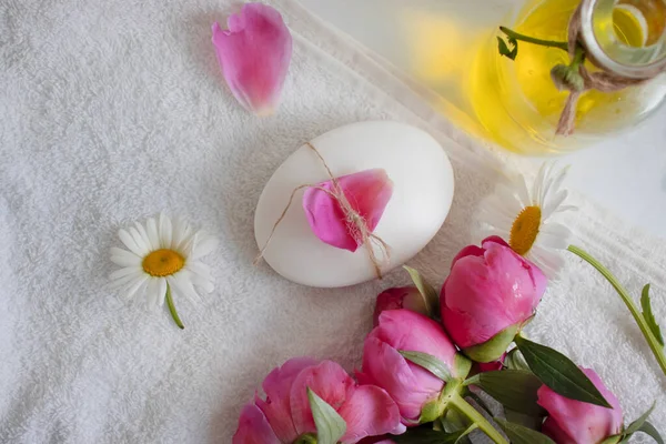 Cosmetic soap, chamomile flower, peony on a light background