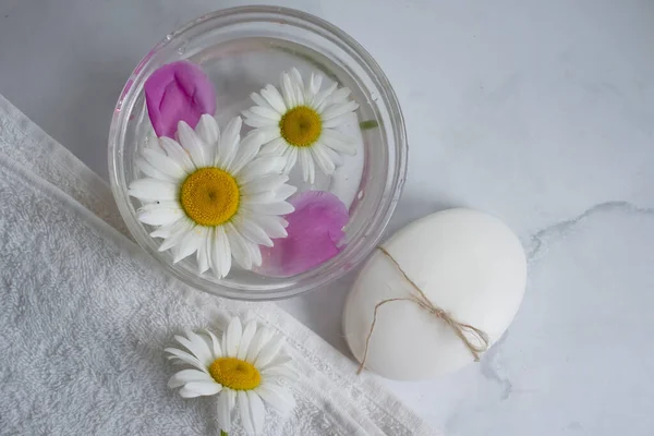 Cosmetic soap, chamomile flower, peony on a light background