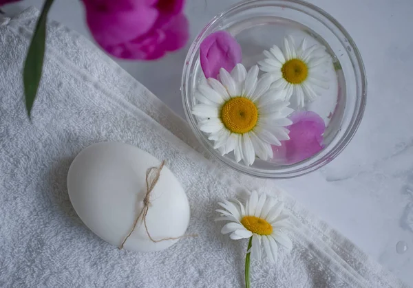 Cosmetic soap, chamomile flower, peony on a light background