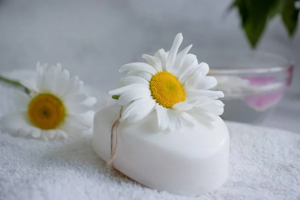 Cosmetic soap, chamomile flower, peony on a light background