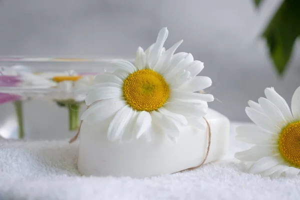 Cosmetic soap, chamomile flower, peony on a light background