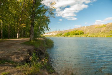 view of the river bank on the shore of the lake and the mountains.