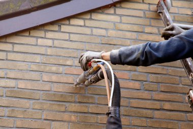 House insulation by injecting microbead pearls in the cavity walls clipart