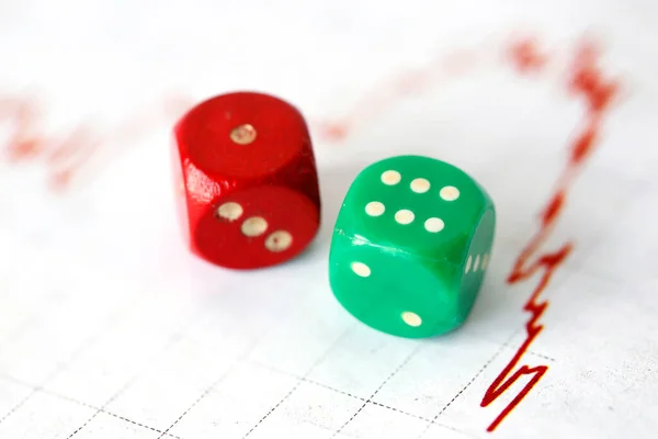 A red and green dice and a financial red trend-line — Stock Photo, Image
