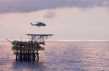 Kıyıdan uzak bir petrol platformunda yakındaki platformlara kabadayılar taşıyan bir helikopter.