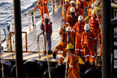 Teçhizat işçileri, Brunei 'deki Güney Çin Denizi' ndeki açık deniz platformlarına naklediliyor. Platforma girmek için bir salıncak ipi kullanılır