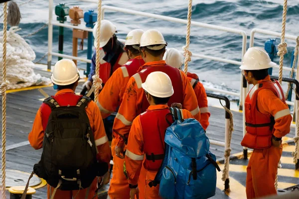 Teçhizat işçileri, Brunei 'deki Güney Çin Denizi' ndeki açık deniz platformlarına naklediliyor. Platforma girmek için bir salıncak ipi kullanılır