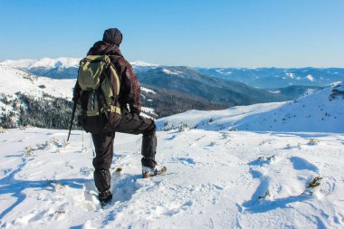 Sırt çantalı bir adam dağlarda yürüyüş yapıyor. Soğuk hava, Peaks 'te kar. Arkaya bak