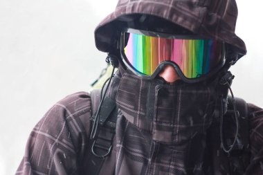 Dağlarda kötü havada sırt çantalı bir turistin portresi. Şiddetli kar fırtınası. Yüzü rüzgar geçirmez bir maskeyle kapatılmış. Sıra dışı kıyafetler. Yakın plan.