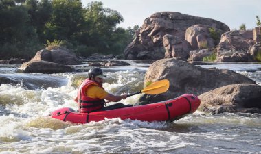 Dağ nehrinin beyaz sularında kürek çeken bir adam. Konsept: ekstrem su sporları, aktif dinlenme, rafting.