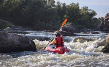 Dağ nehrinin beyaz sularında kürek çeken bir adam. Konsept: ekstrem su sporları, aktif dinlenme, rafting.