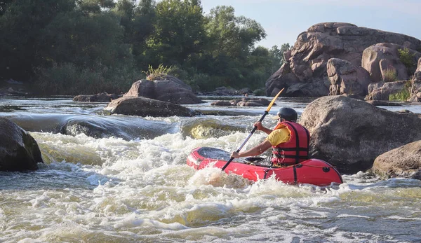 Dağ nehrinin beyaz sularında kürek çeken bir adam. Konsept: ekstrem su sporları, aktif dinlenme, rafting.