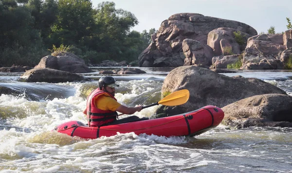 Dağ nehrinin beyaz sularında kürek çeken bir adam. Konsept: ekstrem su sporları, aktif dinlenme, rafting.