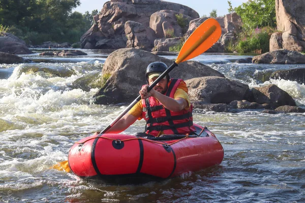 Dağ nehrinin beyaz sularında kürek çeken bir adam. Konsept: ekstrem su sporları, aktif dinlenme, rafting.