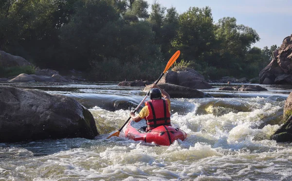 Dağ nehrinin beyaz sularında kürek çeken bir adam. Konsept: ekstrem su sporları, aktif dinlenme, rafting.