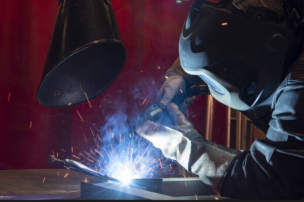 Рабочие, носящие промышленную униформу и сварную железную маску на заводах по сварке стали, концепция промышленной безопасности. сварочный металл