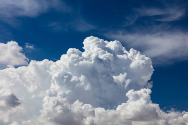 Closeup of Billowy cumulus clouds. Wispy clouds, deep blue sky in background. 