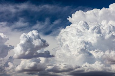 Closeup of Billowy cumulus clouds. Wispy clouds, deep blue sky in background. 