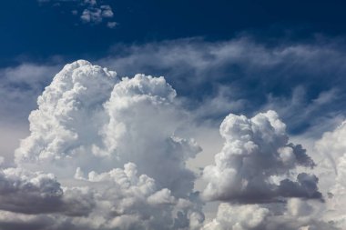 Closeup of Billowy cumulus clouds. Wispy clouds, deep blue sky in background. 