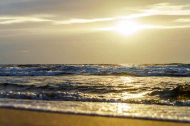 Denizin üzerinde gün batımı. Deniz dalgalarındaki güneş ışığının yansıması. Gün batımındaki gökyüzü. Baltık Denizi.