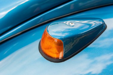 1960 ve 1970 'lerden kalma metalik mavi bir Alman klasik arabasının sol dönüş sinyalinin yan yükseklik görüntüsü.