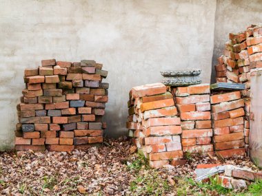 Old cleaned and stacked bricks on a plastered house wall.
