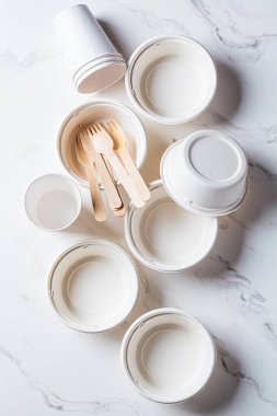 Çevre dostu geri dönüşümlü sofra takımı, sıfır atık konsepti. Kağıt kaseler ve bardaklar beyaz mermer zemin üzerinde, üst görünüm.