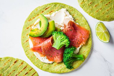 Brokolili yeşil tortilla, avokado, krem peynir ve beyaz mermer kaplama tuzlu somon. Vejetaryen fast food.