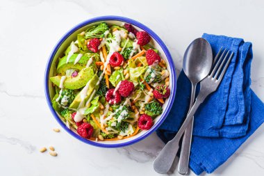Ahududu, çam fıstığı, avokado ve tahini soslu yeşil brokoli salatası. Vejetaryen gıda konsepti.