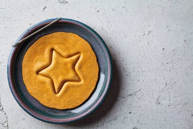 Dalgona Candy - South Korean treat. Round sugar cookie with a star inside, top view. clipart