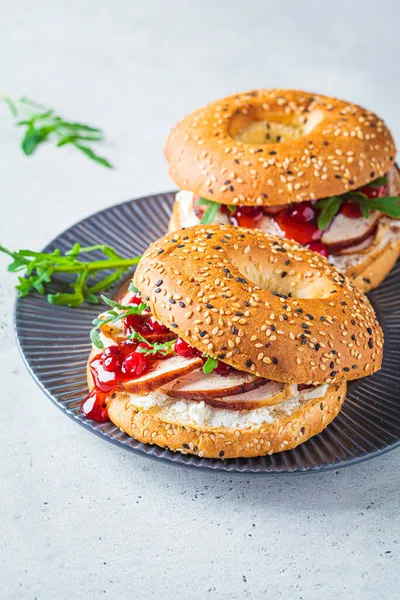 Thanksgiving food concept. Bagel sandwich with turkey and cranberry sauce on gray plate, copy space.
