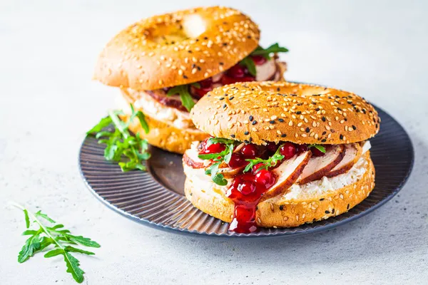 Thanksgiving food concept. Bagel sandwich with turkey and cranberry sauce on gray plate, copy space.