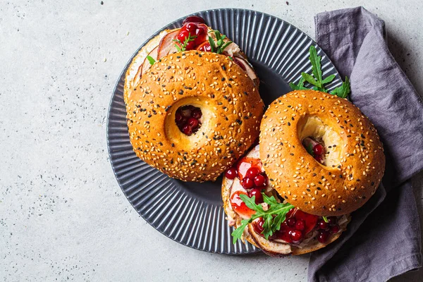 Thanksgiving food concept. Bagel sandwich with turkey and cranberry sauce on gray plate, top view, copy space.