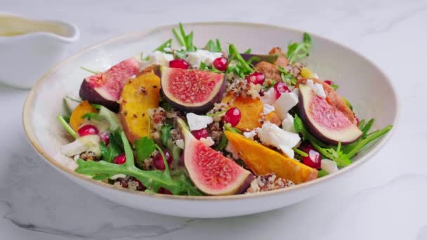 Matlagning varm höst quinoa sallad med bakade grönsaker, fikon, feta, granatäpple och dressing. — Stockvideo