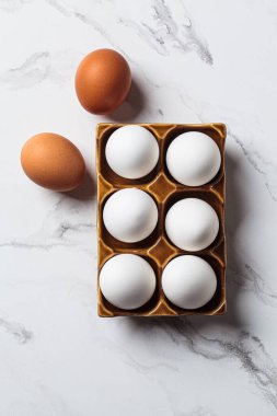 Kahverengi bir stantta beyaz çiğ tavuk yumurtası, beyaz mermer arka plan, üst manzara..