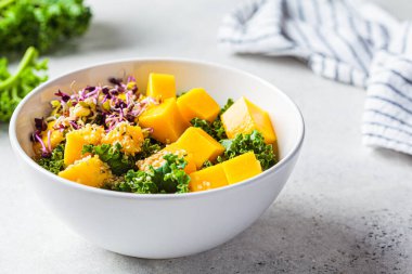 Lahanalı detoks salatası, mango ve lahanalar beyaz kasede. Vejetaryen yemeği, sağlıklı bitki temelli diyet konsepti..