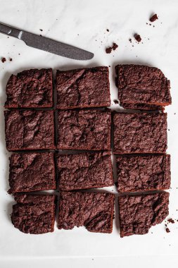 Beyaz bir masada vejetaryen browni kareleri, üst manzara. Bitki temelli tatlı konsepti.