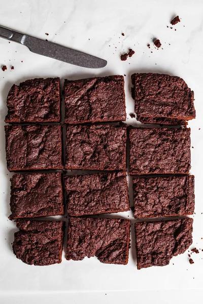 Beyaz bir masada vejetaryen browni kareleri, üst manzara. Bitki temelli tatlı konsepti.