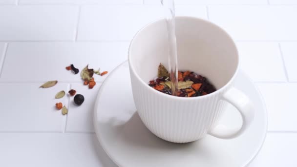 用浆果倒入杯子的草药茶，放在厨房的白色瓷砖背景上，复制空间，慢动作. — 图库视频影像